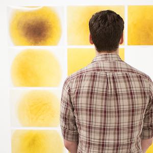 Man looking at yellow abstract painting